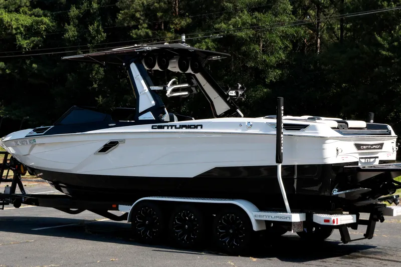 Slide: The Image of 2022 Centurion Ri265 boat on trailer, parked outdoors with lush greenery background. - 26