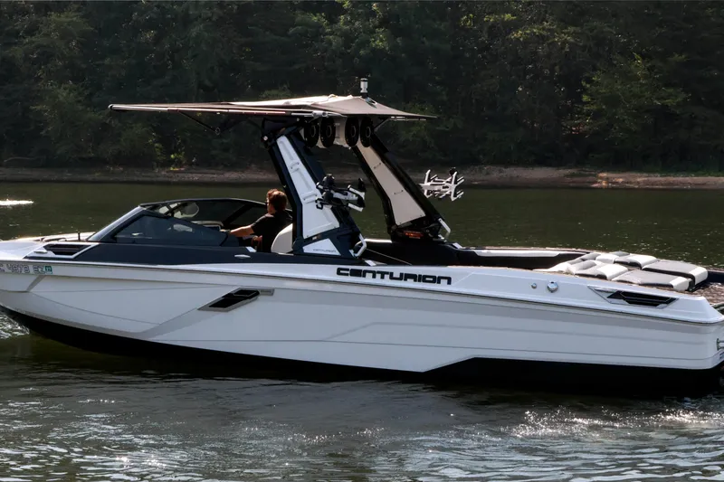Slide: The Image of 2022 Centurion Ri265 boat cruising on a calm lake with lush forest background. - 12