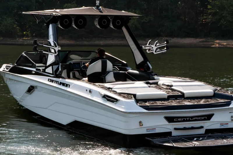 Slide: The Image of 2022 Centurion Ri265 boat cruising on a calm lake with lush greenery in the background. - 10