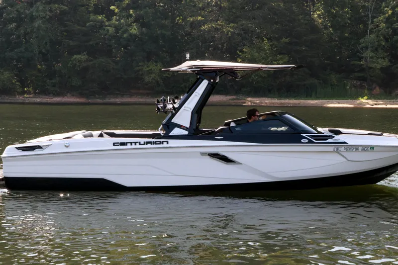 Slide: The Image of 2022 Centurion Ri265 boat cruising on a calm lake with lush forest backdrop. - 5