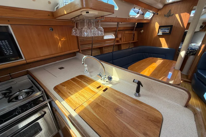Slide: The Image of Interior of 2003 Catalina 380 yacht featuring kitchen and dining area with wood finishes. - 17