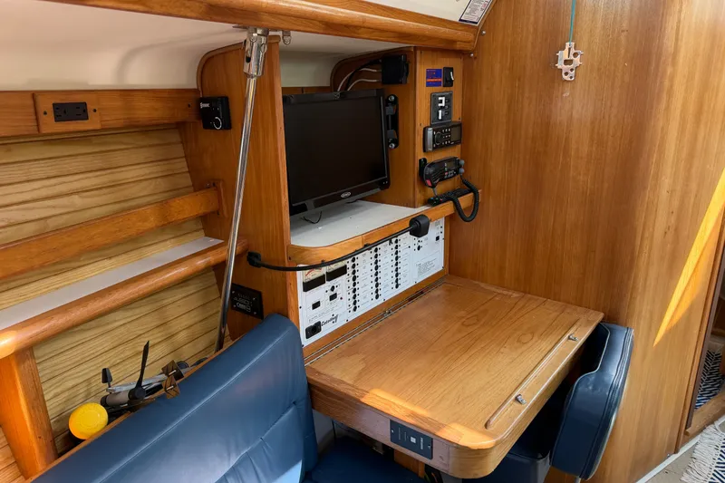 Slide: The Image of Navigation station inside a 2003 Catalina 380 sailboat with wooden finish and control panel. - 24