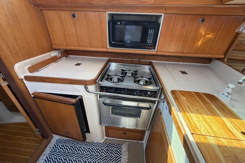 Slide: The Image of Compact kitchen in a 2003 Catalina 380 sailboat with stove, microwave, and wooden cabinetry. - 16