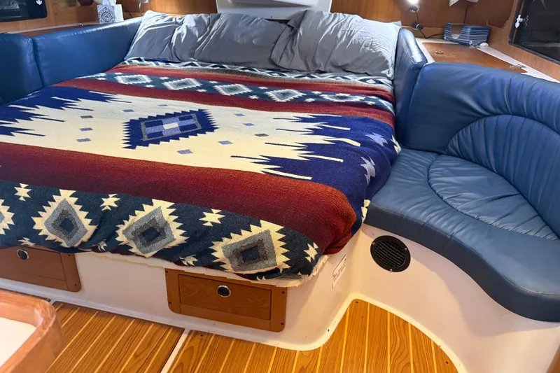 Slide: The Image of Cozy cabin interior of 2003 Catalina 380 with patterned blanket and blue seating. - 15