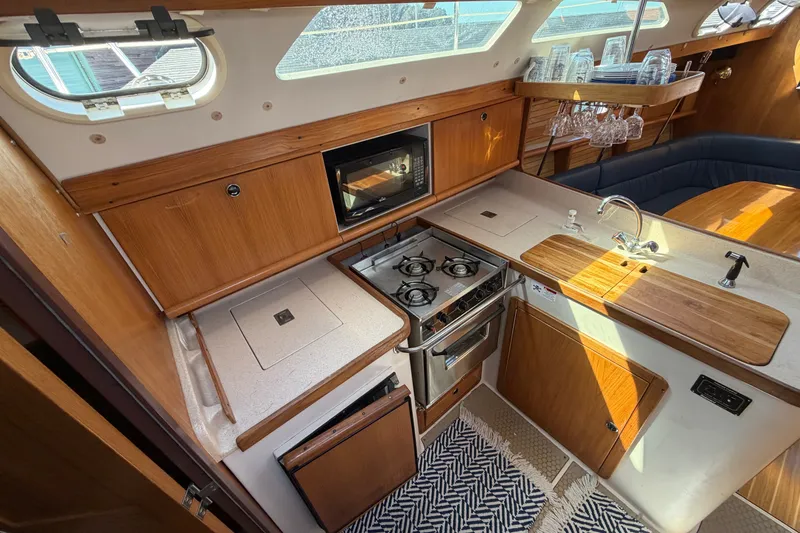 Slide: The Image of Interior of 2003 Catalina 380 sailboat kitchen with stove, sink, and wooden cabinetry. - 9