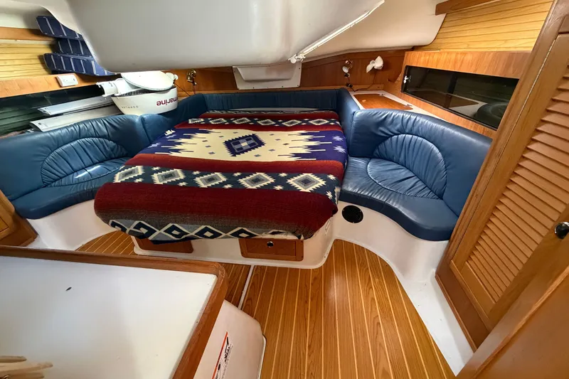 Slide: The Image of Cozy cabin interior of 2003 Catalina 380 sailboat with patterned blanket and blue seating. - 4