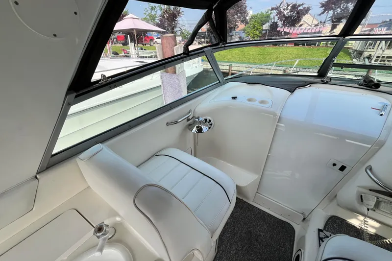 Slide: The Image of 1995 Sea Ray Sundancer 330 cockpit with white seating and dashboard, docked near a garden. - 5