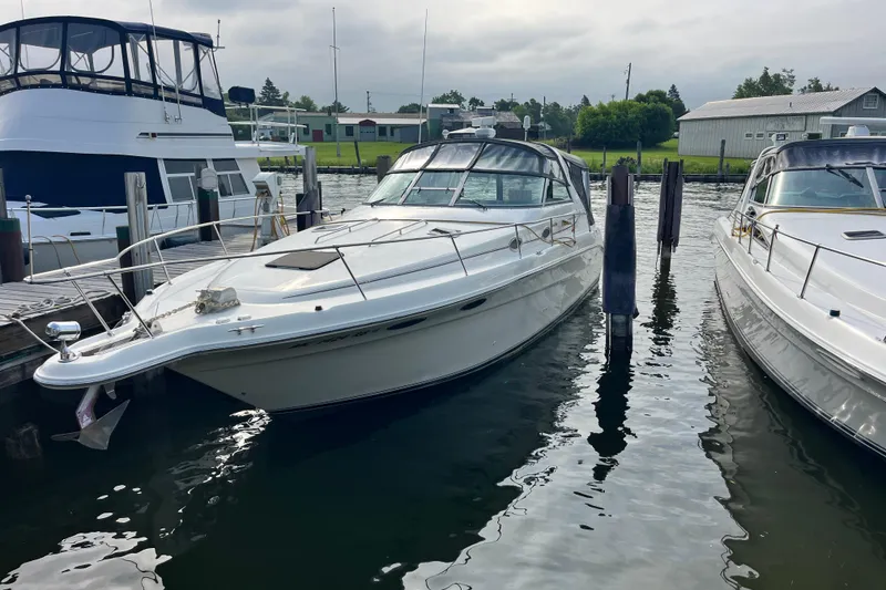 The Image of 1995 Sea Ray Sundancer 330 docked at marina, surrounded by calm water. - 1