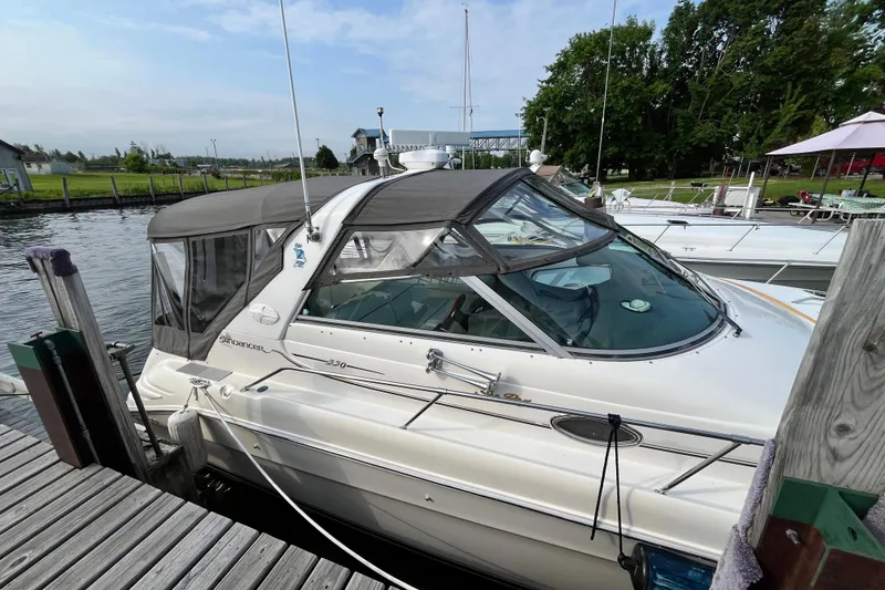 Slide: The Image of 1995 Sea Ray Sundancer 330 docked at a marina, featuring a sleek design and covered cockpit. - 3