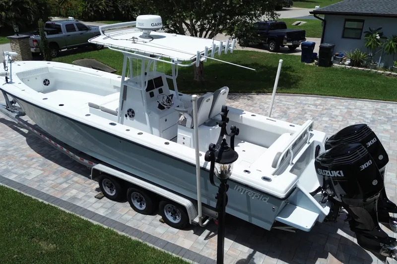 Slide: The Image of 1995 Intrepid 323 Open boat with dual Suzuki 300 engines on a trailer in a driveway. - 2