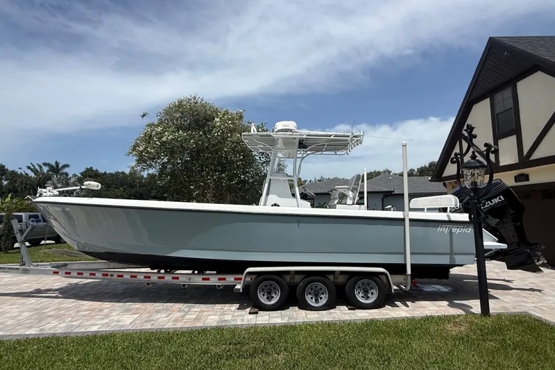 Slide: The Image of 1995 Intrepid 323 Open boat on trailer, parked in driveway under clear sky. - 73