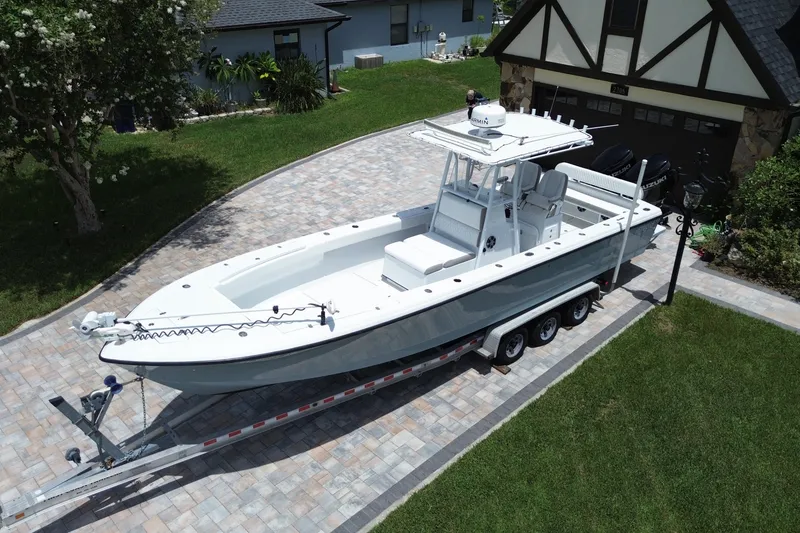 Slide: The Image of 1995 Intrepid 323 Open boat on trailer in driveway, surrounded by greenery and houses. - 8