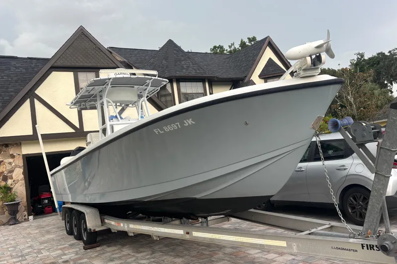 The Image of 1995 Intrepid 323 Open boat on trailer in driveway, Tudor-style house background. - 1