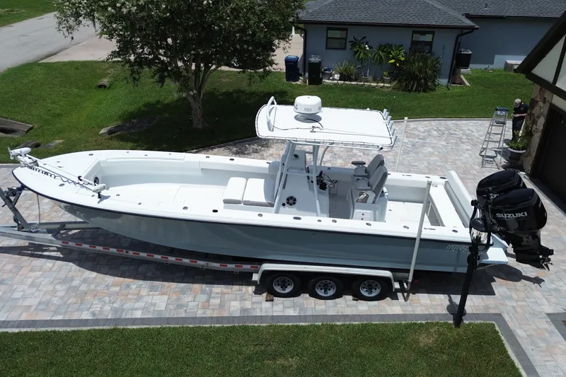 Slide: The Image of 1995 Intrepid 323 Open boat on trailer in driveway, featuring dual Suzuki outboard motors. - 7