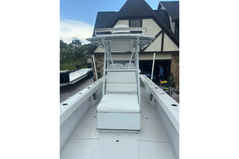 Slide: The Image of 1995 Intrepid 323 Open boat with white seating, parked near a house. - 12