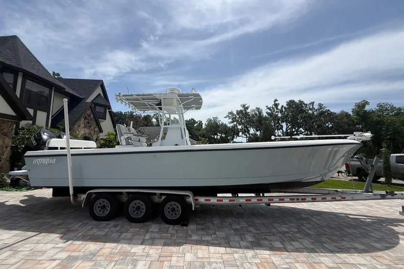 Slide: The Image of 1995 Intrepid 323 Open boat on trailer, parked in a driveway under a clear sky. - 76