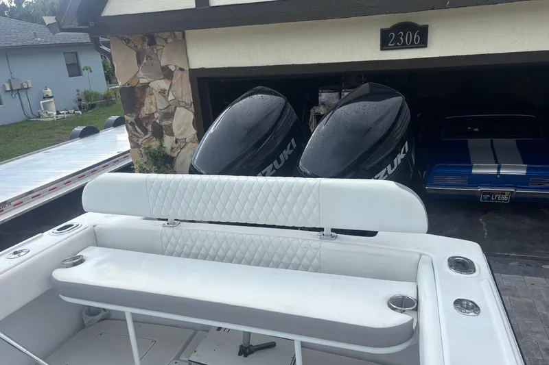 Slide: The Image of 1995 Intrepid 323 Open boat with Suzuki engines parked near a garage. - 10