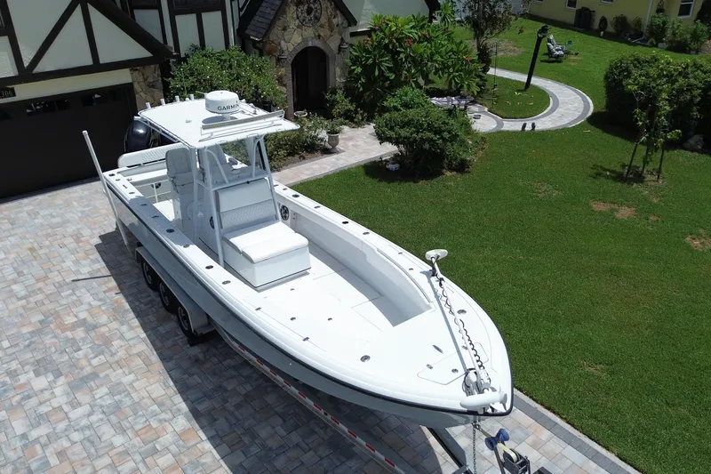 Slide: The Image of 1995 Intrepid 323 Open boat on trailer in residential driveway, surrounded by greenery. - 5