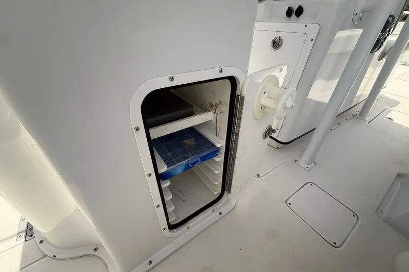 Slide: The Image of Open storage compartment on 1995 Intrepid 323 Open boat, featuring shelves and a blue container. - 17
