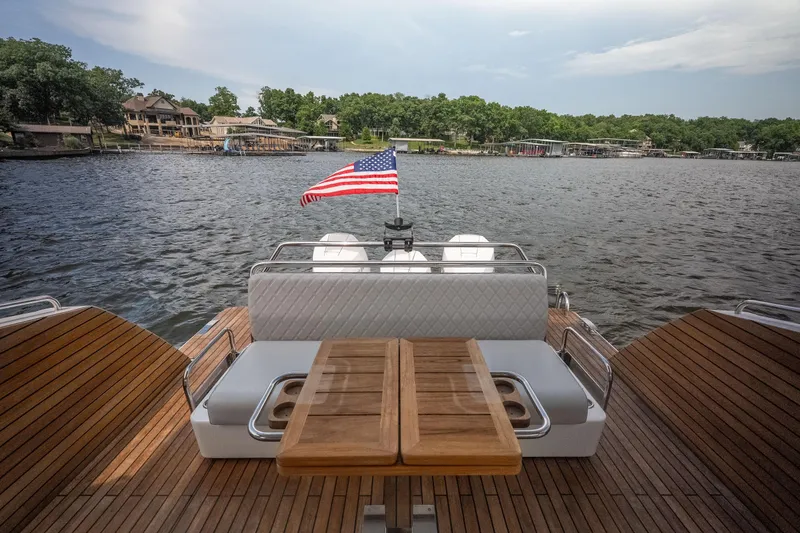 Slide: The Image of Schaefer 375 yacht, 2024 model, with American flag, wooden deck, and scenic lake view. - 10