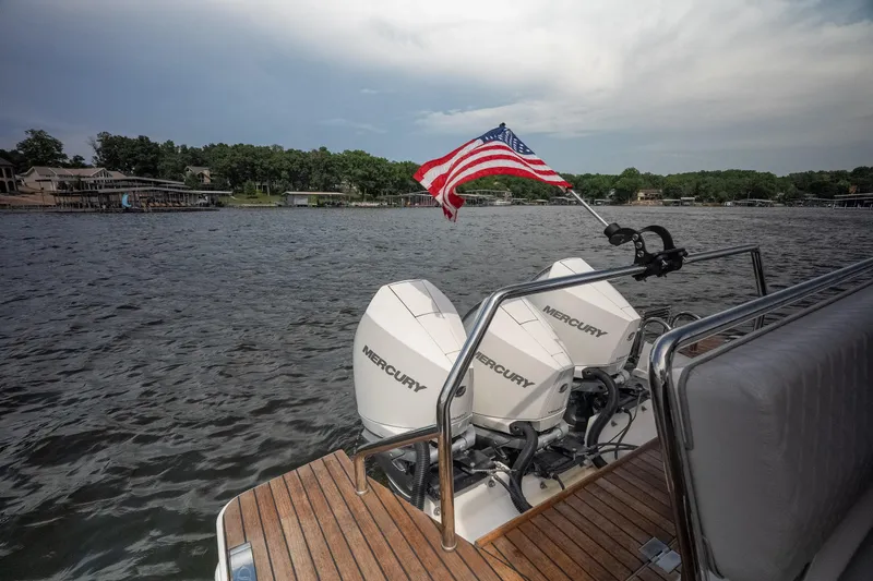 Slide: The Image of Schaefer 375 boat with dual Mercury engines and American flag on a lake, 2024 model. - 12