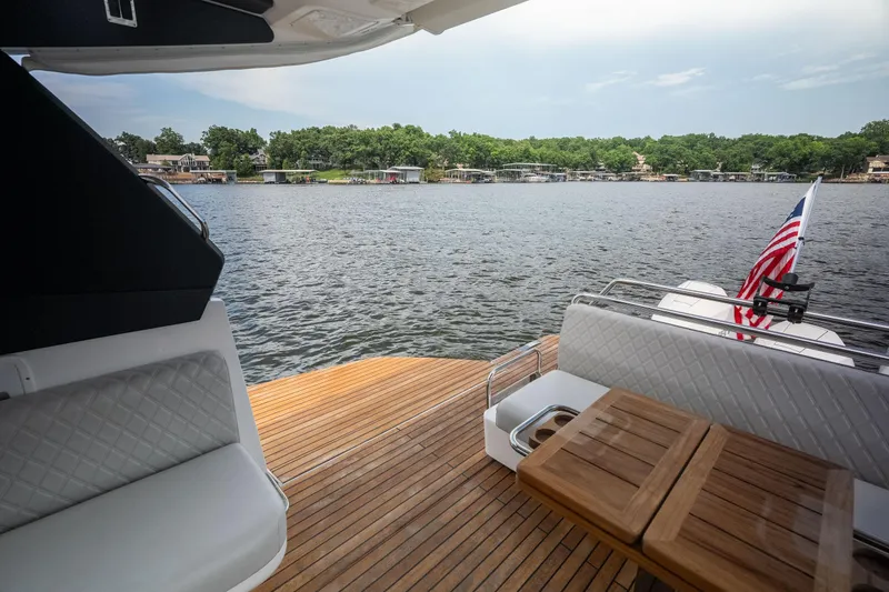 Slide: The Image of Luxury Schaefer 375 yacht deck with seating, wooden table, and scenic waterfront view, 2024 model. - 28