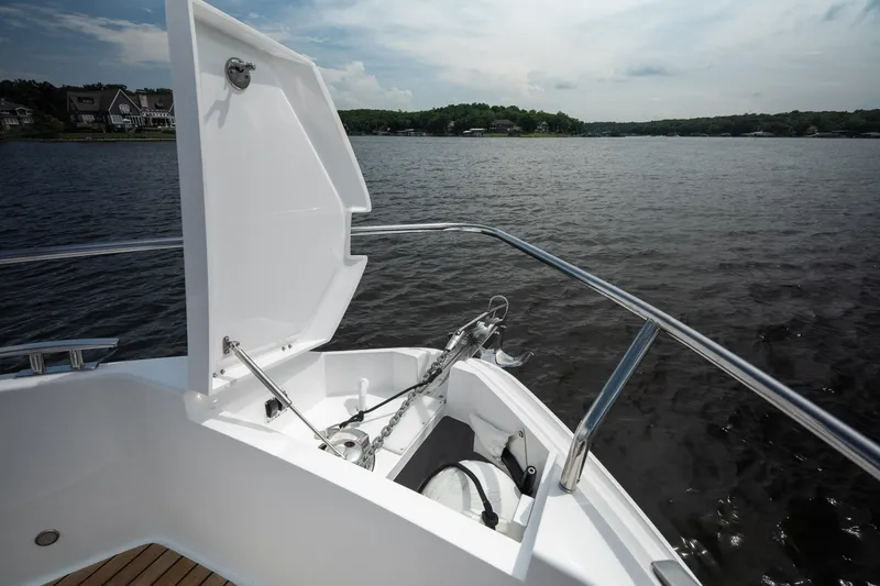 Slide: The Image of 2024 Schaefer 375 yacht bow with anchor compartment open on a serene lake. - 45