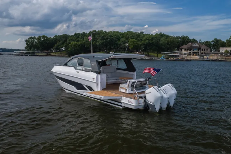 Slide: The Image of 2024 Schaefer 375 yacht cruising on a lake with American flag, surrounded by trees and houses. - 9