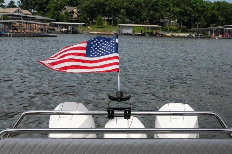 Slide: The Image of 2024 Schaefer 375 boat with American flag on lake, surrounded by docks and trees. - 47