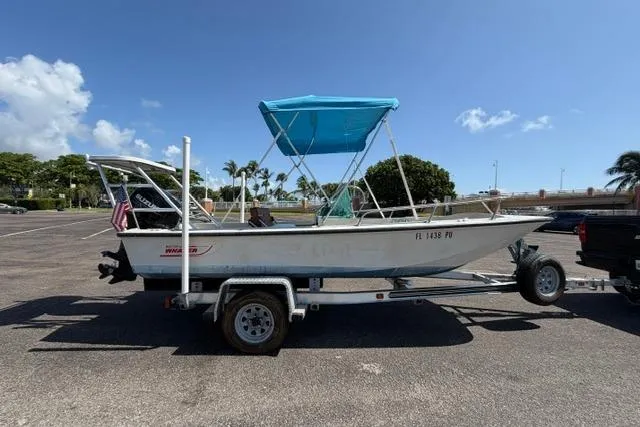 Slide: The Image of 1990 Boston Whaler 17 Newport boat on trailer, blue canopy, parked outdoors. - 4