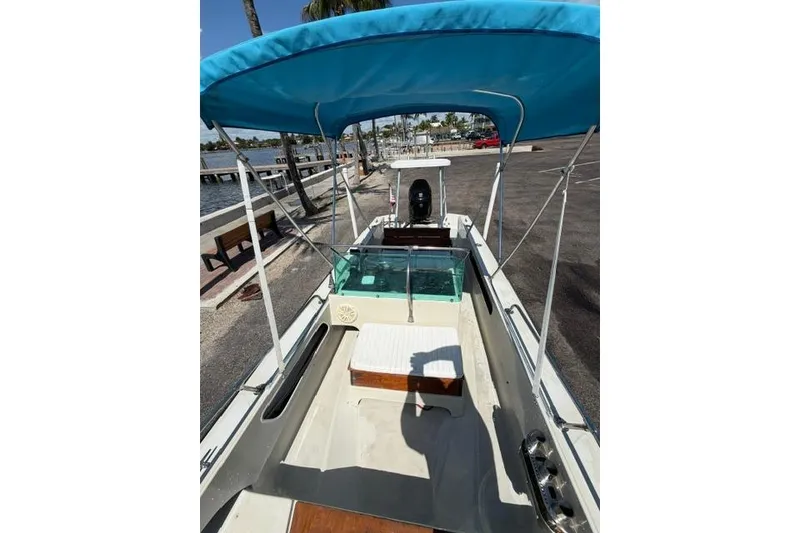 Slide: The Image of 1990 Boston Whaler 17 Newport boat with blue canopy, docked near waterfront. - 8