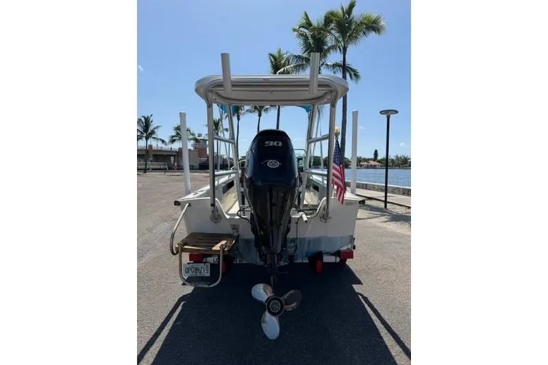 Slide: The Image of 1990 Boston Whaler 17 Newport boat with outboard motor, parked near waterfront. - 3