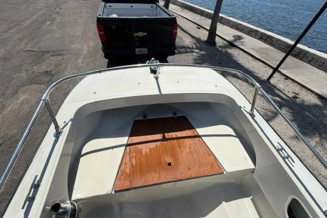Slide: The Image of 1990 Boston Whaler 17 Newport boat on trailer near waterfront, with pickup truck in background. - 7