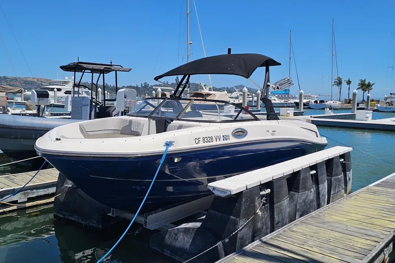 Slide: The Image of A 2021 Bayliner VR6 Bowrider I/O docked. It features a black canopy and white railing. - 13