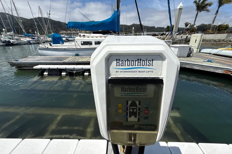 Slide: The Image of HarborHoist boat lift control panel at marina with docked sailboats in background. - 18