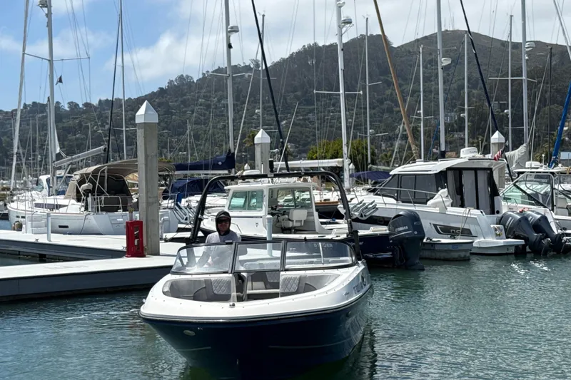 Slide: The Image of 2021 Bayliner VR5 Bowrider I/O docked in a marina with sailboats and hills in the background. - 12