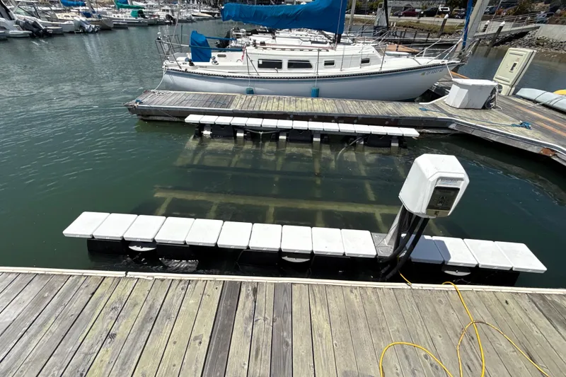 Slide: The Image of Docked sailboat near a marina with floating platforms and electrical hookup. - 17