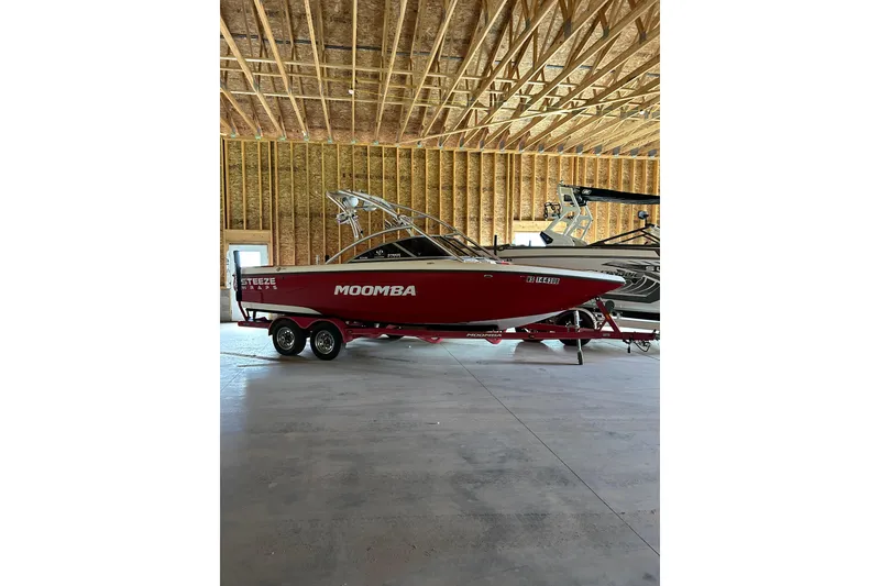 The Image of Red 2004 Moomba Mobius XLV boat on trailer in a wooden garage. - 0