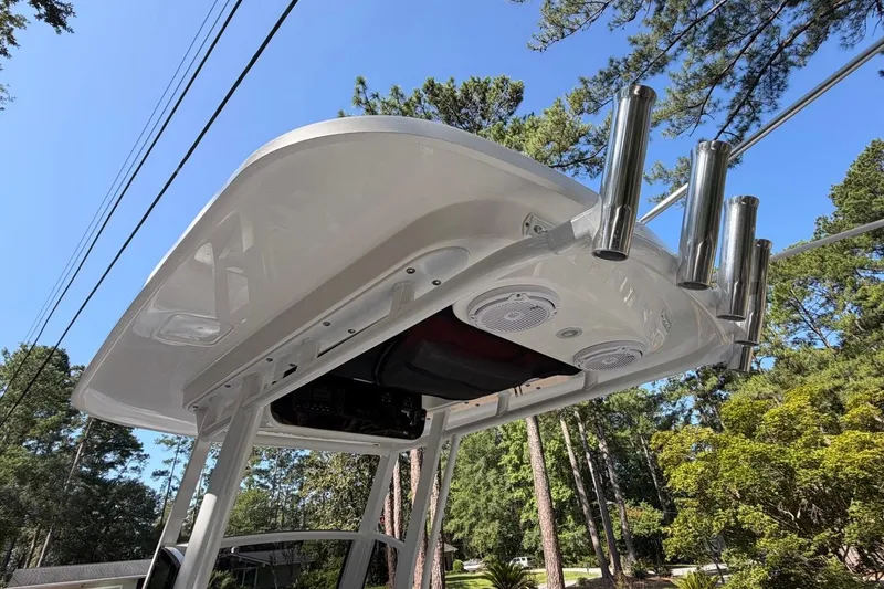Slide: The Image of 2019 Edgewater 230CC boat T-top with rod holders and speakers, surrounded by trees. - 22