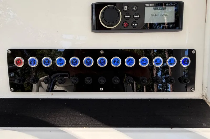 Slide: The Image of Control panel of a 2019 Edgewater 230CC boat with various switches and a Fusion audio system. - 19