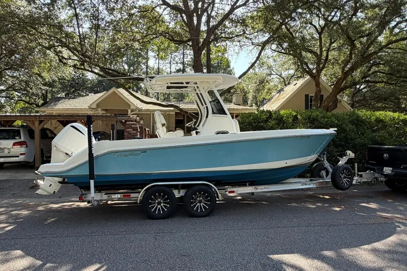 The Image of 2019 Edgewater 230CC boat on trailer, parked in residential driveway with trees and house. - 1