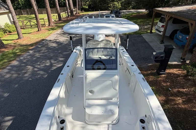 Slide: The Image of 2019 Edgewater 230CC boat parked on a driveway, surrounded by trees and vehicles. - 11