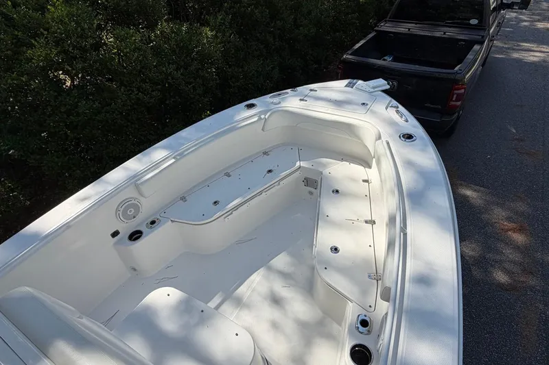 Slide: The Image of 2019 Edgewater 230CC boat interior, white seating, parked near a black truck. - 8