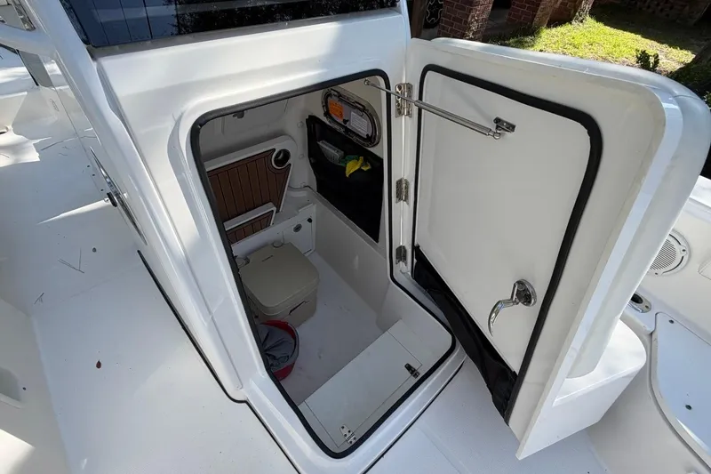 Slide: The Image of 2019 Edgewater 230CC boat interior storage compartment with open door, showcasing organized space. - 12