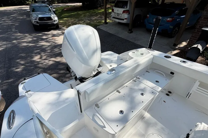 Slide: The Image of 2019 Edgewater 230CC boat with outboard motor, parked near vehicles in a driveway. - 25