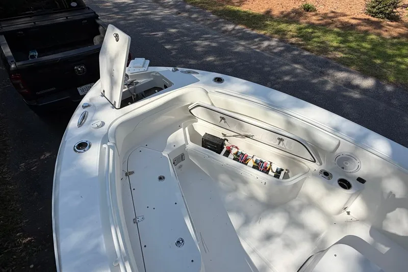Slide: The Image of 2019 Edgewater 230CC boat interior with open storage compartment, parked near a truck. - 9