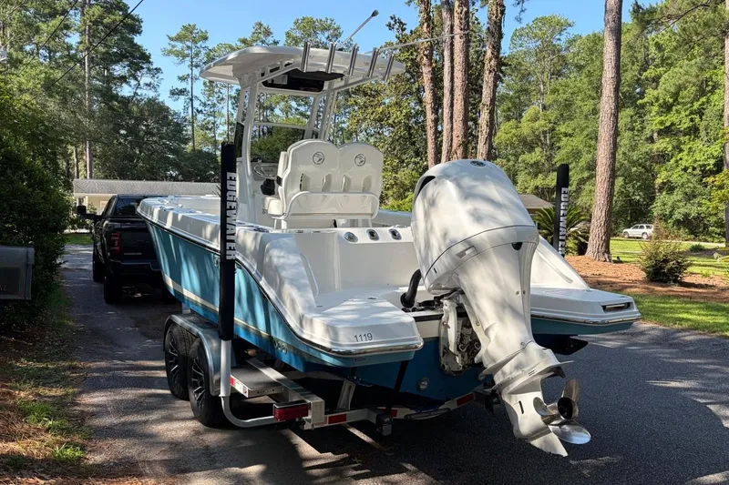 Slide: The Image of 2019 Edgewater 230CC boat on trailer, parked in a wooded residential area. - 4