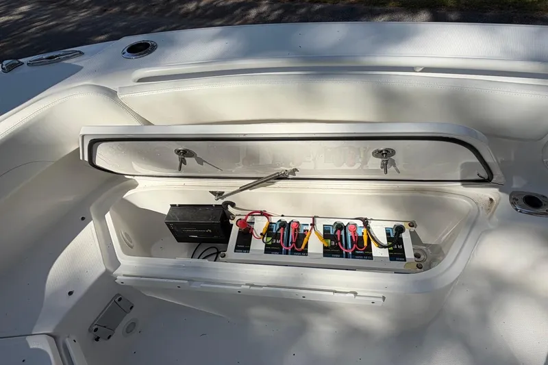 Slide: The Image of 2019 Edgewater 230CC boat battery compartment with wiring and storage. - 10
