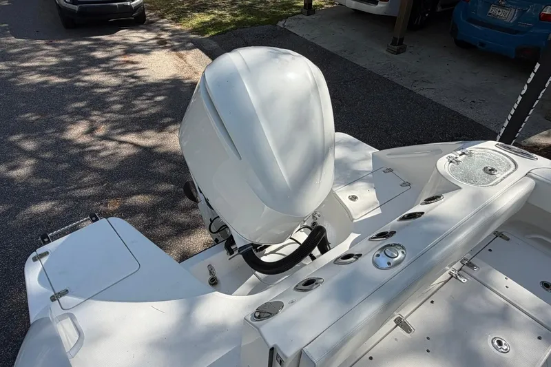 Slide: The Image of 2019 Edgewater 230CC boat with outboard motor, parked on a shaded street. - 27