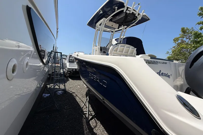 Slide: The Image of 2018 Robalo R222 Explorer boat in storage, side view under clear blue sky. - 22